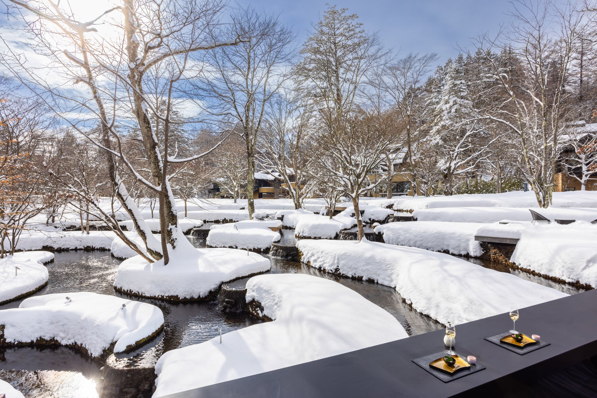 雪に覆われた星のや軽井沢の棚田ラウンジと水辺の景色
