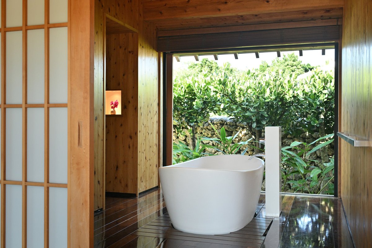 木の格子戸と障子に囲まれた客室の浴室で、開け放した窓の向こうに緑の庭が見える白いバスタブ