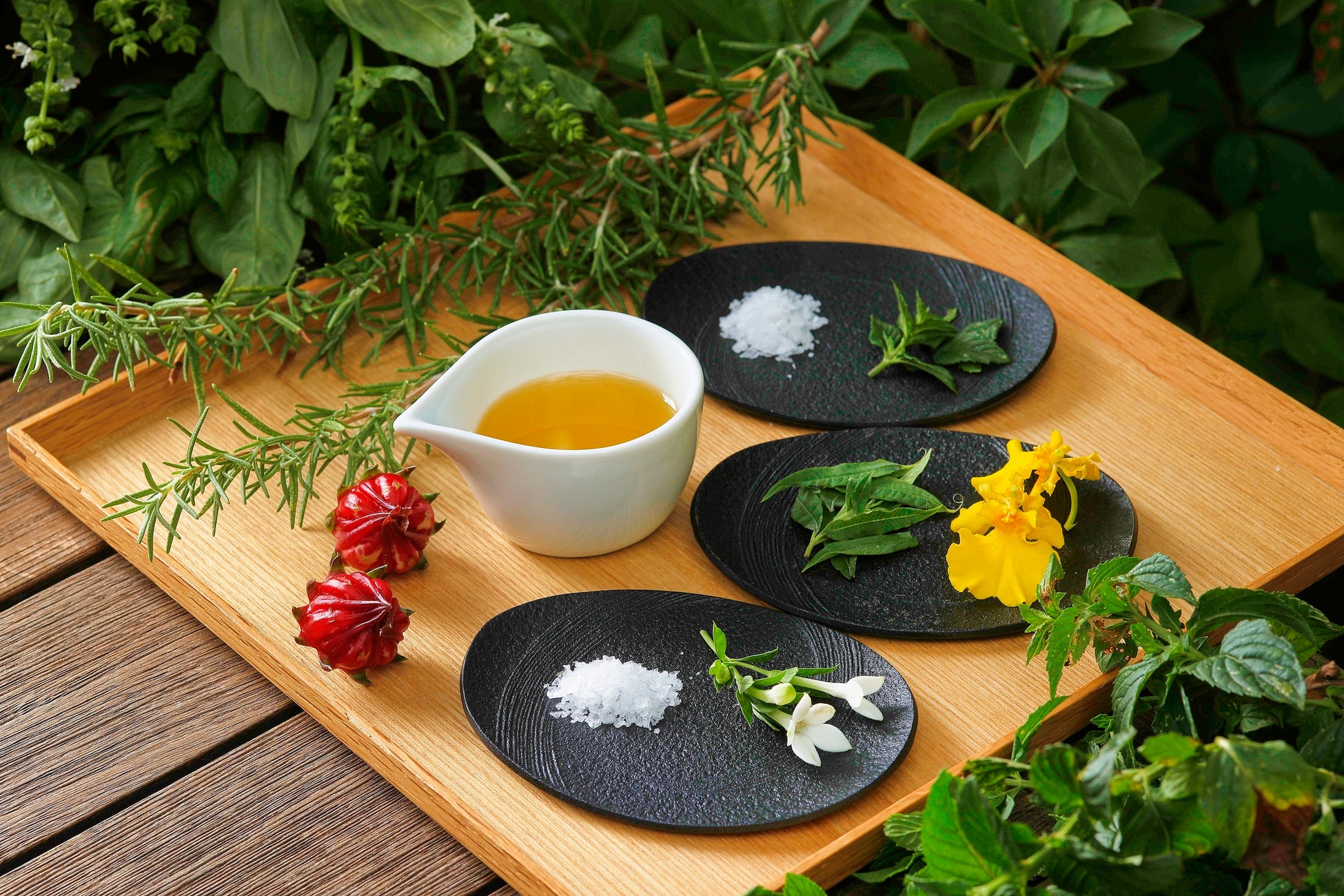 木のトレーに並ぶオイルと塩、ハーブや花